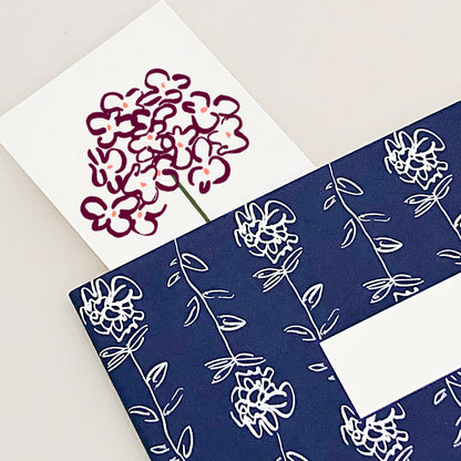 A close-up of a floral bookmark in a navy notebook.