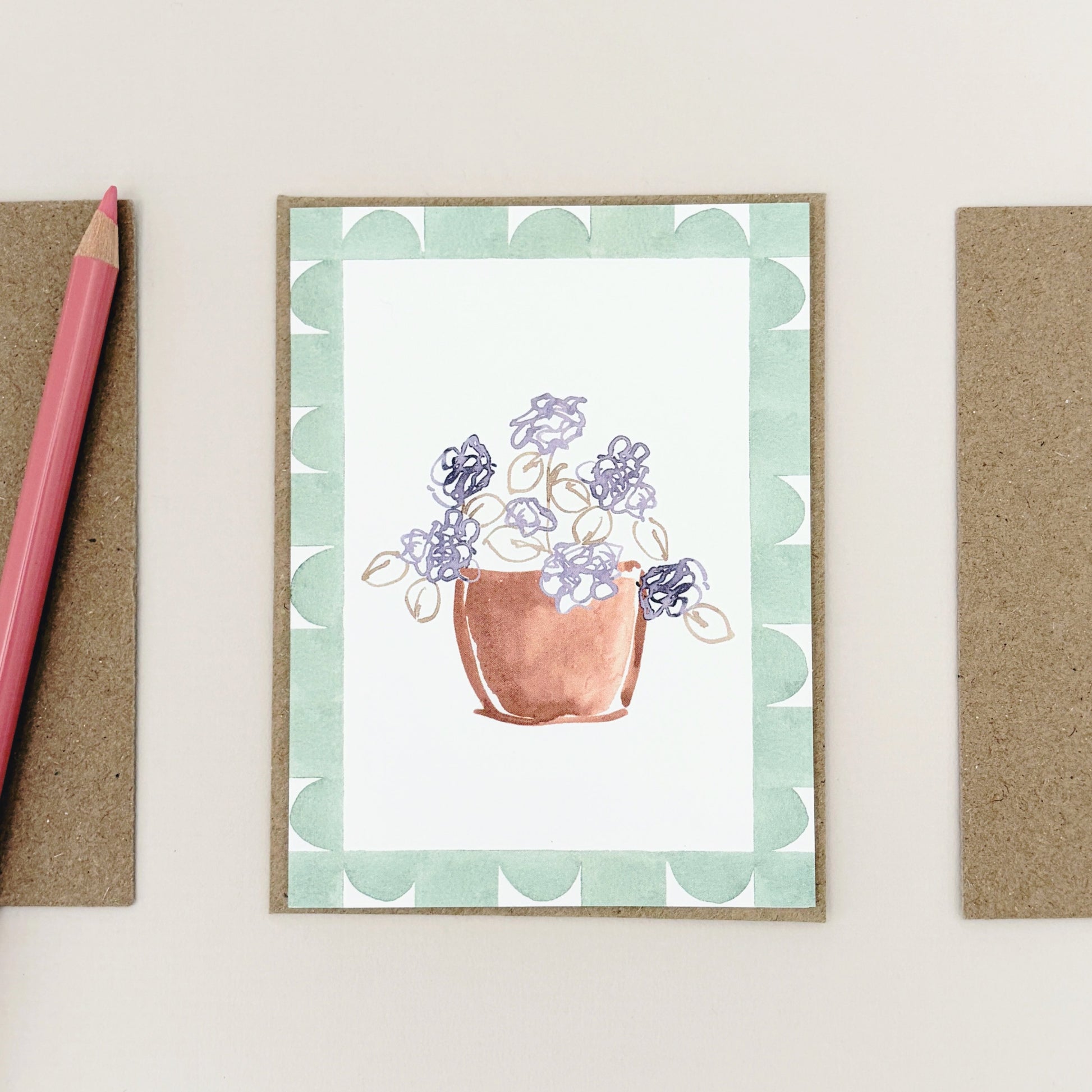 A purple summer bloom in a terracotta pot. Painted onto an off white background with a green geometric border.