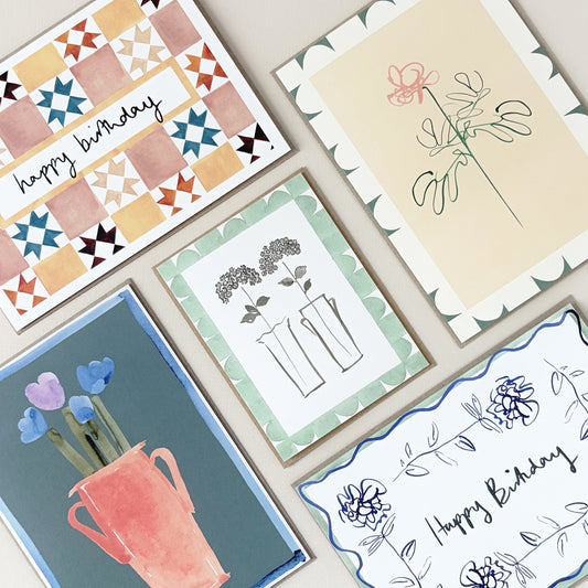 A selection of greeting cards laid flat on a table with various designs and text.