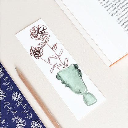 A white bookmark with Ranunculus flowers in a green vase