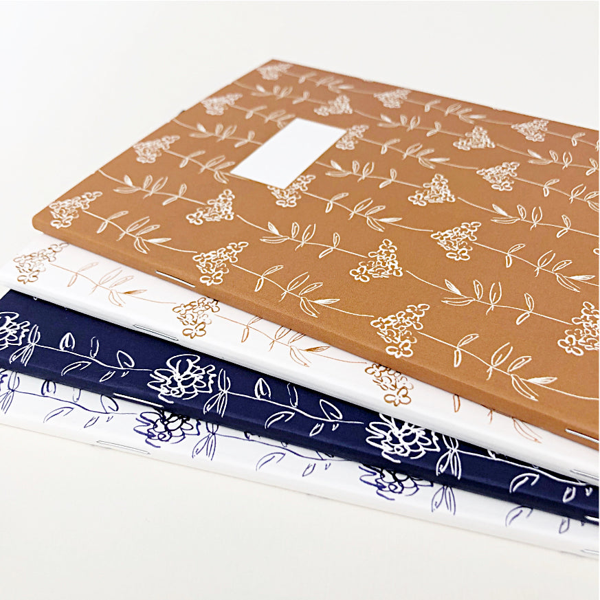 Stack of 3 hand-designed notebooks with floral illustrations in different colours